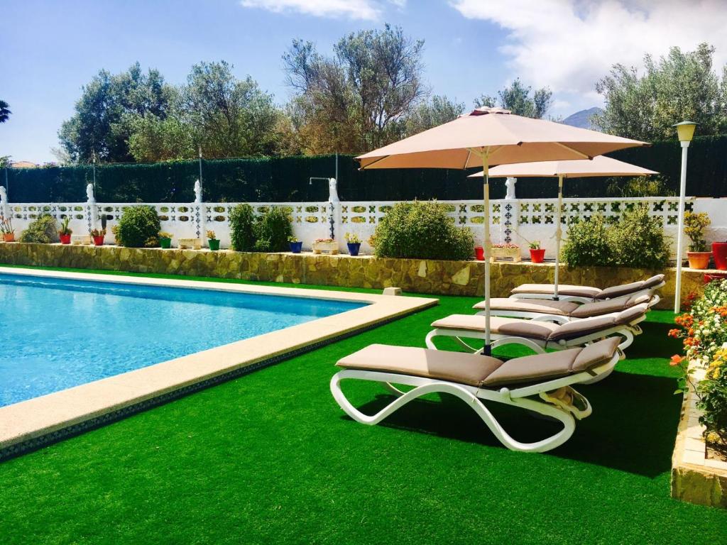 een groep ligstoelen en een parasol naast een zwembad bij Villa Salteri in Benidorm