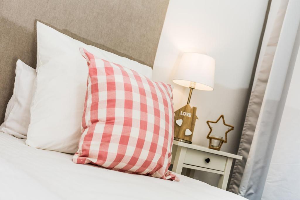 almohada rosa y blanca sentada en una cama en Apartamentos Cornellalux 2, en Cornellà de Llobregat