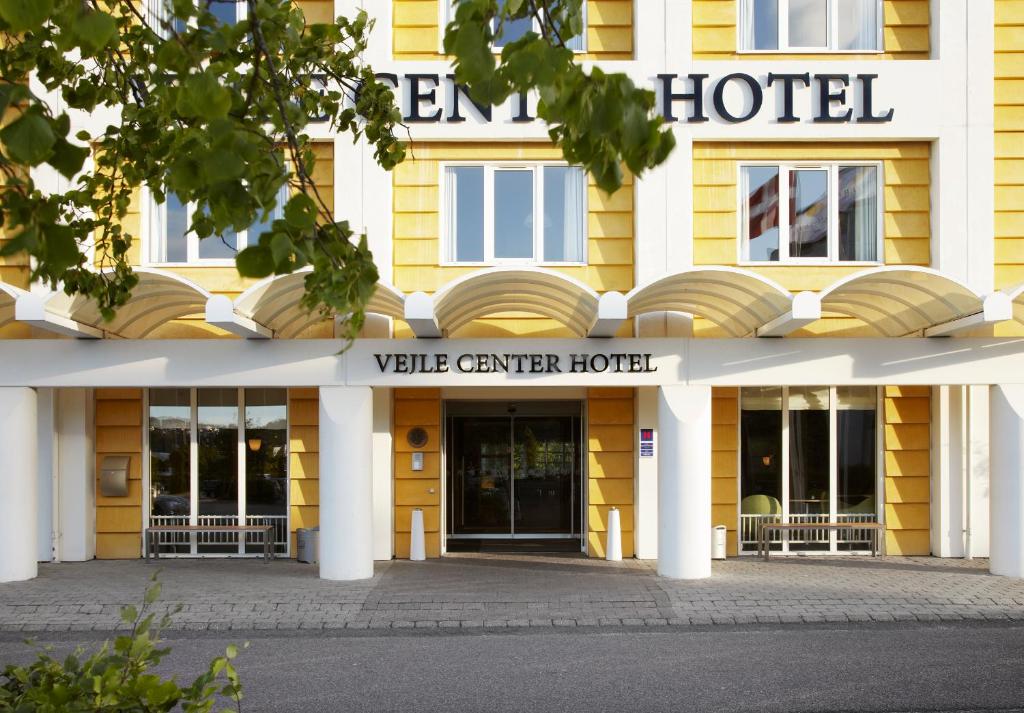 a hotel with a yellow building with the front entrance at Vejle Center Hotel in Vejle