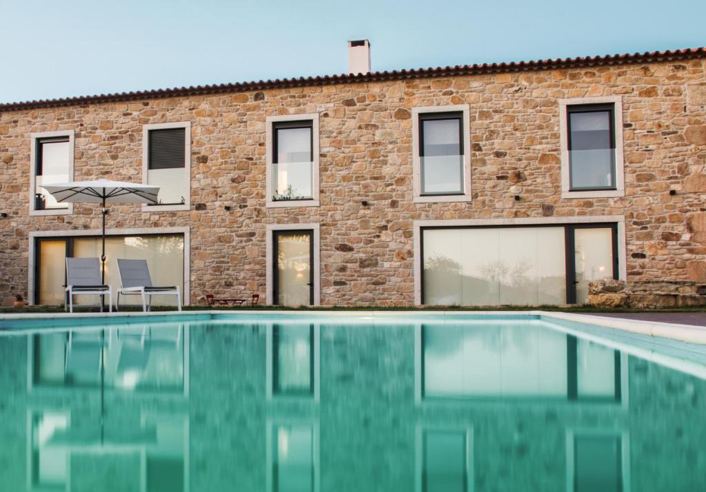 a swimming pool in front of a brick building at Casa de Belharino in Miranda do Douro