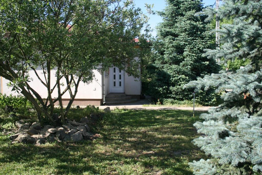 un giardino con una porta bianca e alberi di Levendula Apartman Nyíregyháza a Nyíregyháza