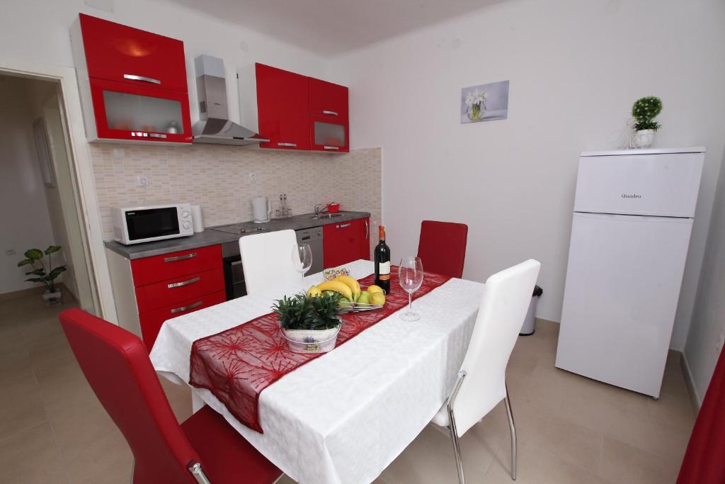 una cocina con mesa con sillas y una cocina con armarios rojos. en Apartman Seaside Paradise en Split