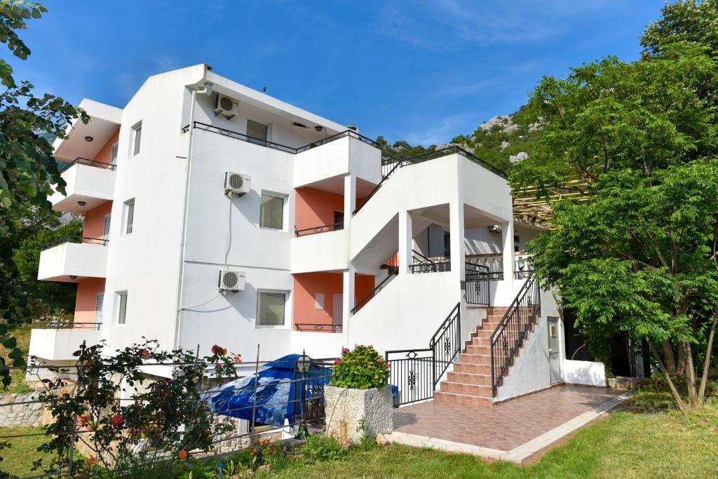 biały budynek apartamentowy ze schodami i drzewami w obiekcie Apartmani Stanisic w mieście Čanj