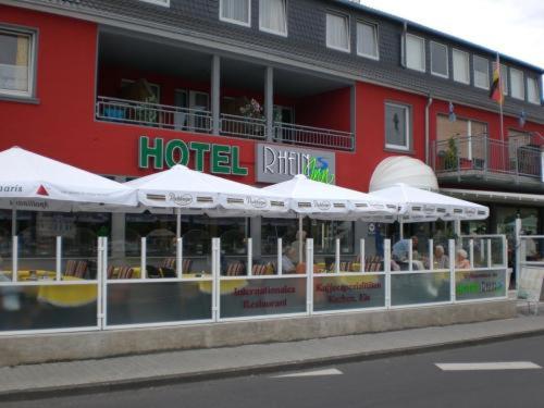 um hotel com guarda-sóis brancos em frente a um edifício em Hotel Rhein INN em Remagen