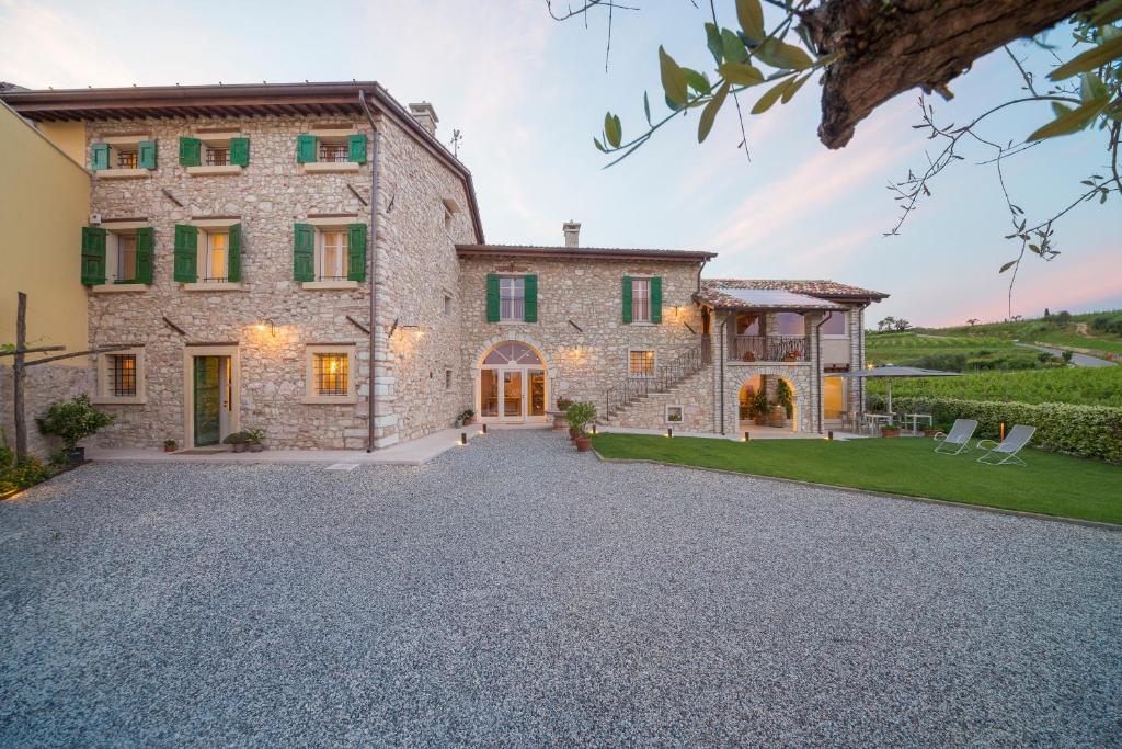 an external view of a large stone house with a driveway at Corte Formigar in SantʼAmbrogio di Valpolicella