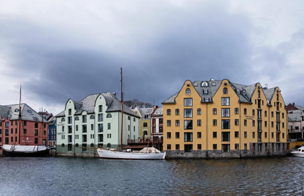 un grupo de edificios con un barco en el agua en Hotel Brosundet en Ålesund