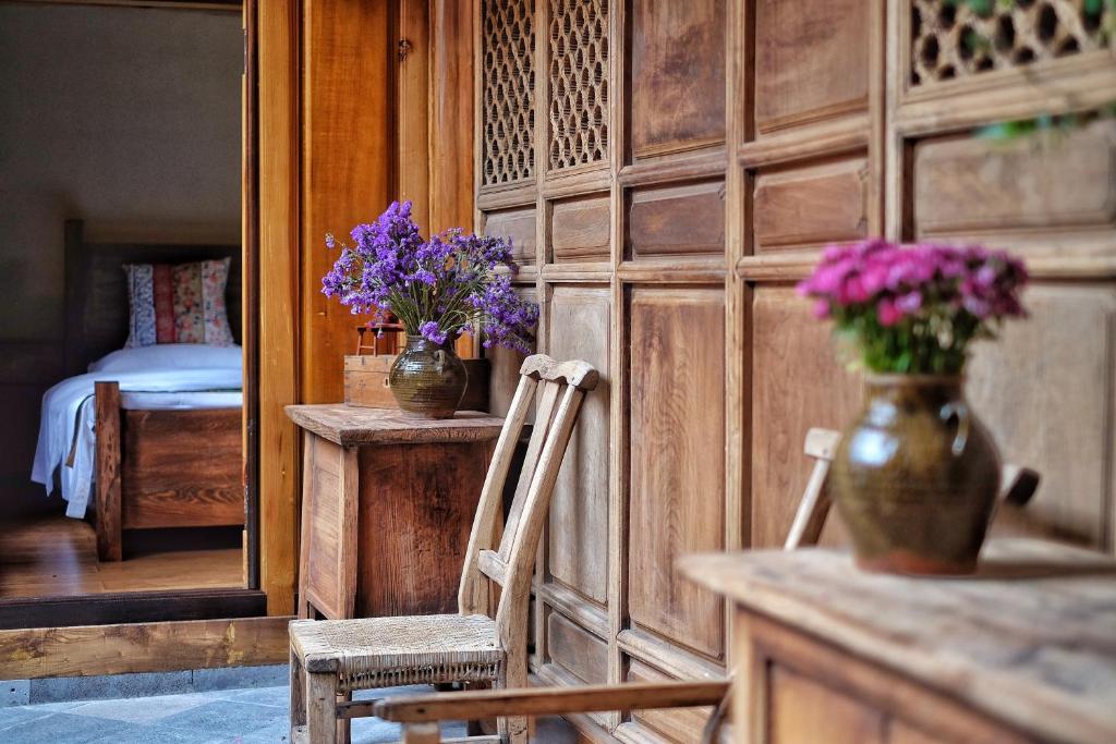 une chambre avec deux chaises et des vases de fleurs violettes dans l'établissement Dream Bay, à Tengchong