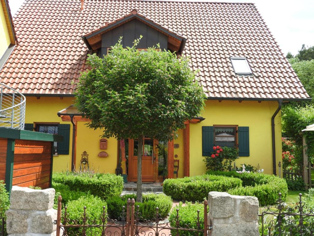 Una casa amarilla con un árbol delante. en Sweet Home Suite, en Hallerndorf