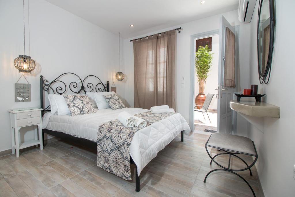 a white bedroom with a bed and a chair at Relax Studios in Naxos Chora