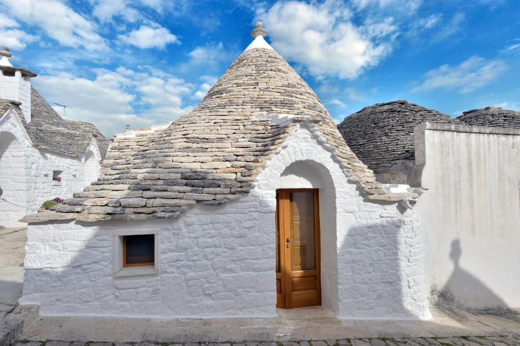 mały biały budynek z dachem z drzwiami w obiekcie Suite Curcuma w Alberobello
