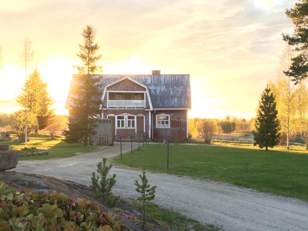 una casa en un campo con el sol en el fondo en Guesthouse Kumpunen en Petäjävesi