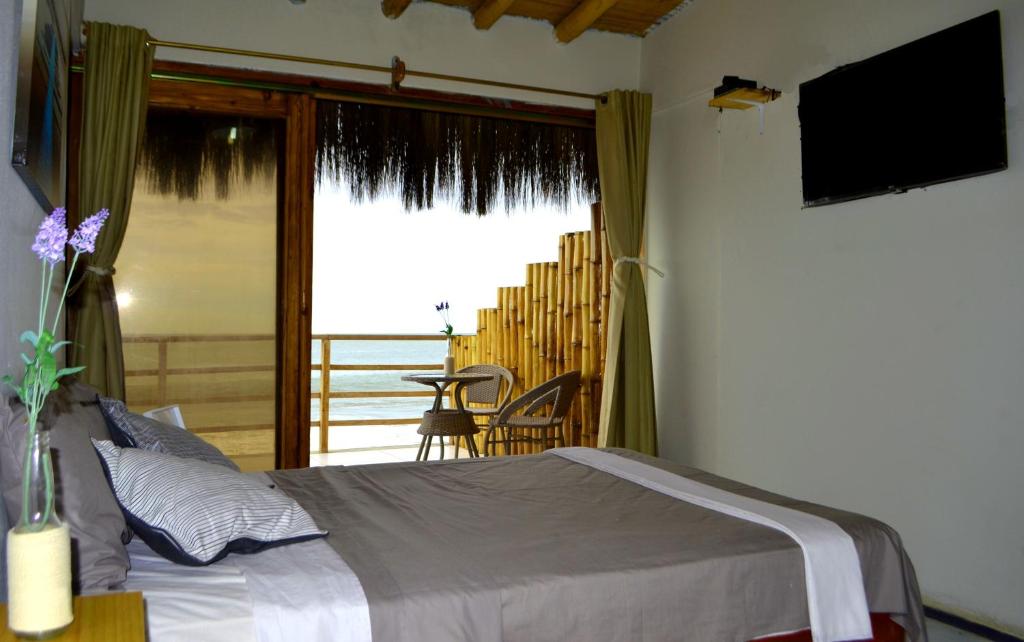 a bedroom with a bed and a balcony with a television at B&B Las Playitas in Máncora