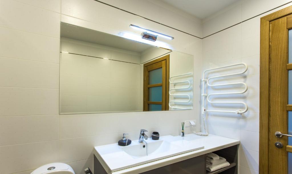 a white bathroom with a sink and a mirror at Violetos Lux Apartamentai in Druskininkai