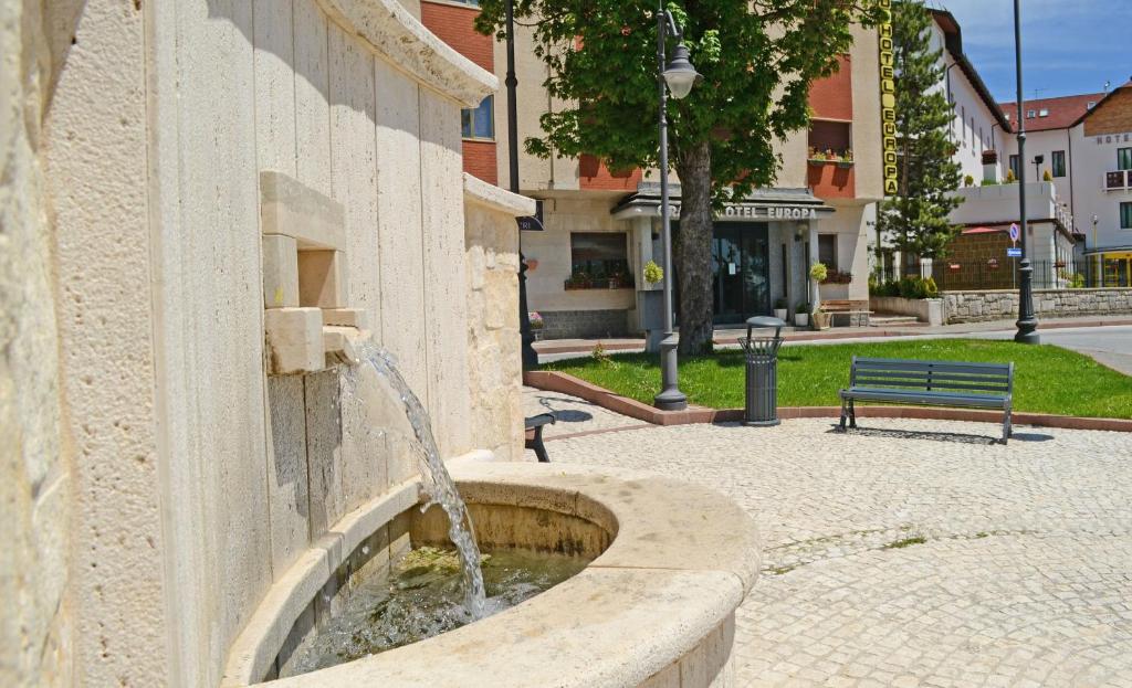 una fuente en el lateral de un edificio con un banco en Grand Hotel Europa, en Rivisondoli