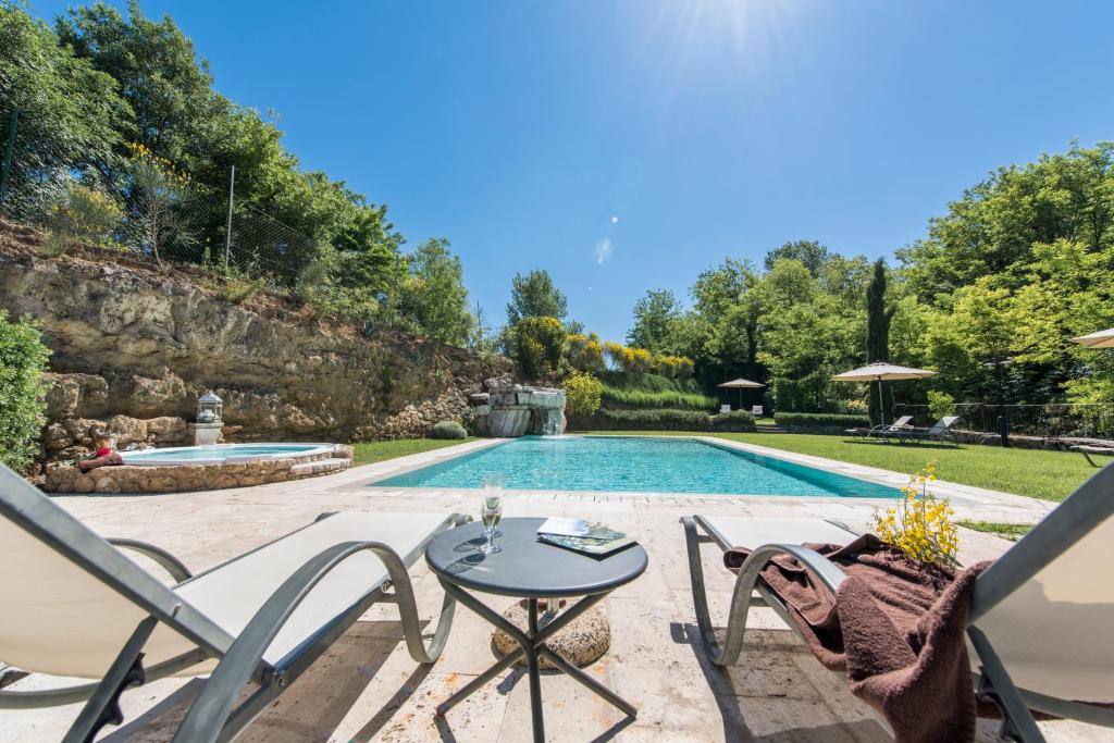 een patio met een tafel en stoelen naast een zwembad bij Molino Della Lodola in Rapolano Terme