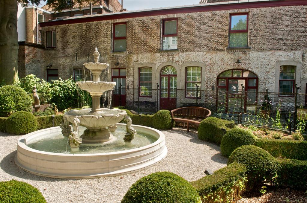 una fuente en un jardín frente a un edificio en Hotel Jan Brito, en Brujas