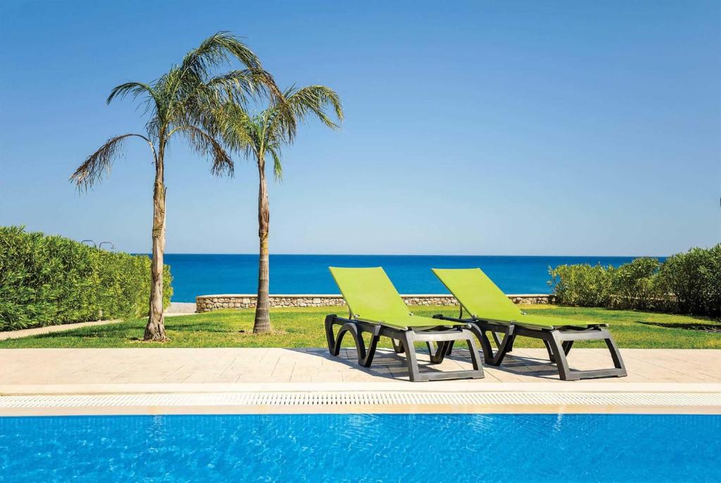 two green chairs sitting next to a swimming pool at Tsampikos in Gennadi