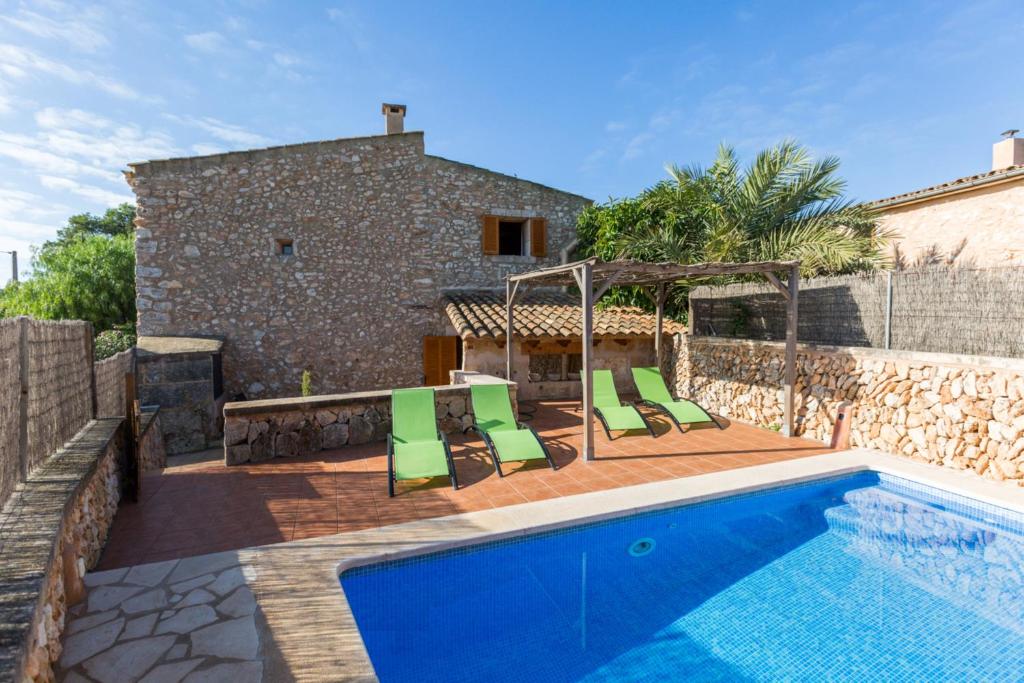 a pool with green chairs and a house at Casa Rural Sa Sorda in Campos
