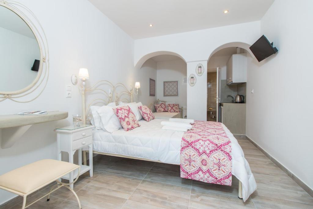 a bedroom with a white bed with pink pillows at Relax Studios in Naxos Chora