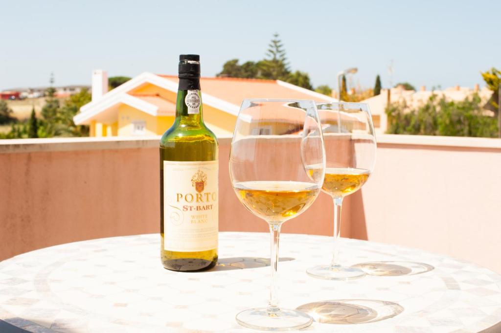 a bottle of wine and two wine glasses on a table at Grace Villa in Aldeia de Juso