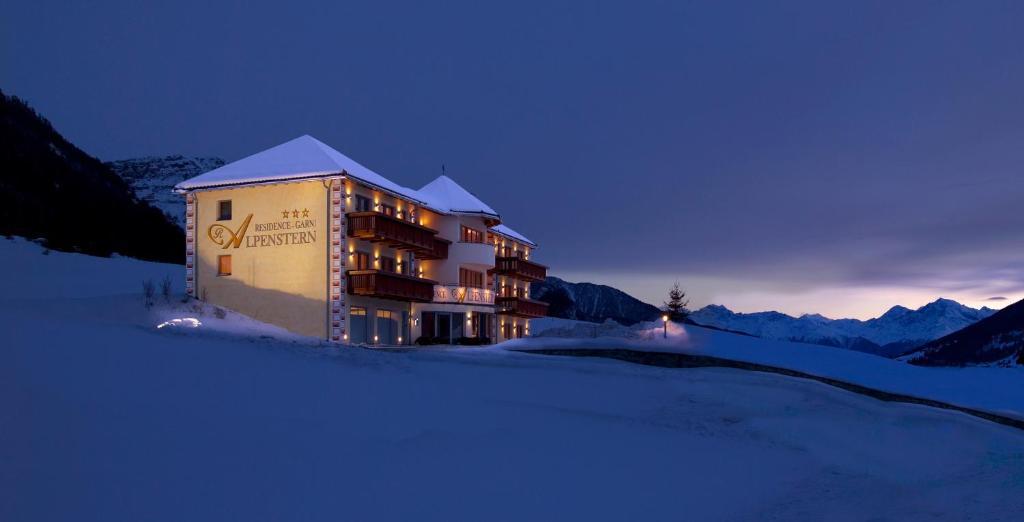 a building in the snow at night with mountains at Residence Garni Alpenstern in Resia
