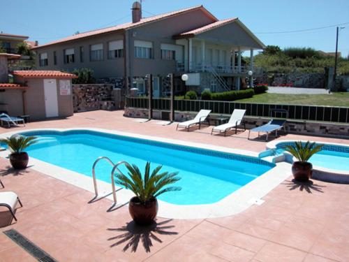 a swimming pool in front of a house at Pension Asun Sanxenxo in Sanxenxo