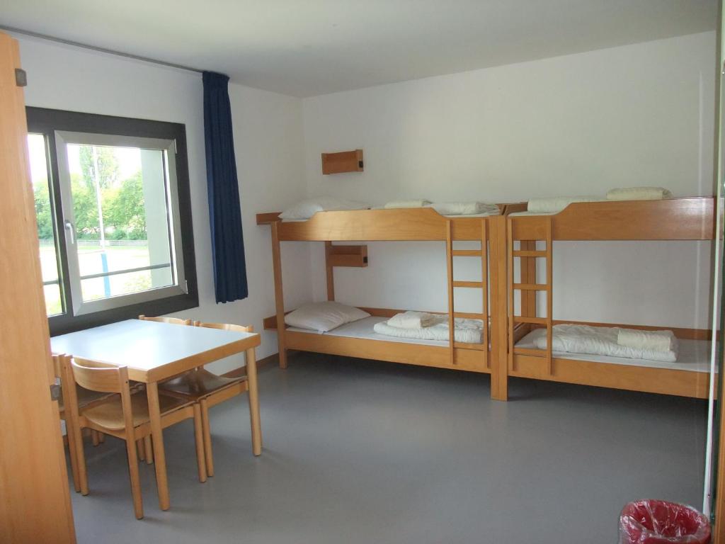 Zimmer mit 2 Etagenbetten, einem Tisch, einem Tisch und einem Stuhl in der Unterkunft Jugendherberge Heidelberg International in Heidelberg