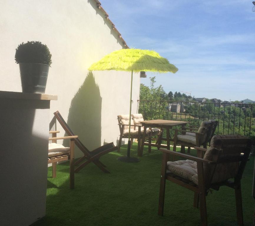 a patio with a table and chairs and an umbrella at Les Parenthèses Occitanes - Maison Del Traouc in Bozouls