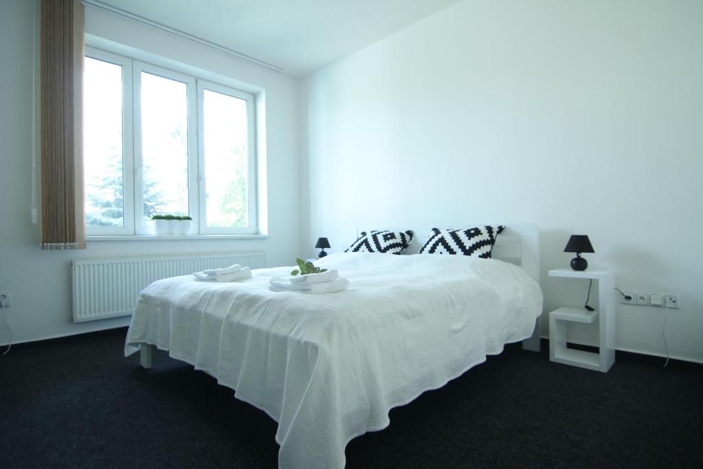 a white bedroom with a large white bed with white sheets at Apartman Amanda in Poděbrady