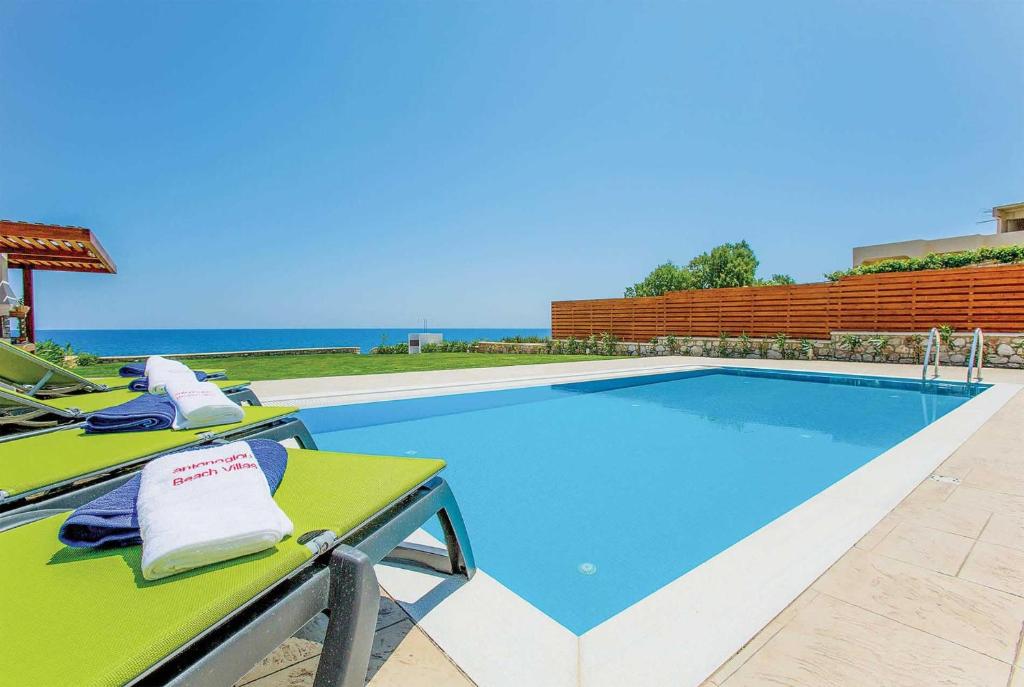 a swimming pool with two lounge chairs and the ocean at Metis in Gennadi