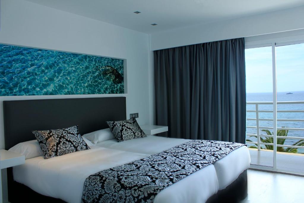 a bedroom with a large bed and a large window at Hotel Náutico Ebeso in Ibiza Town