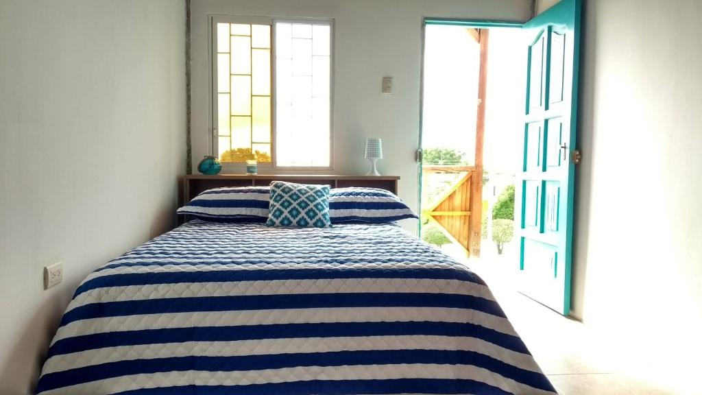 ein Schlafzimmer mit einem Bett mit einer blau-weißen gestreiften Decke in der Unterkunft Guest House Villa Machalilla in Machalilla