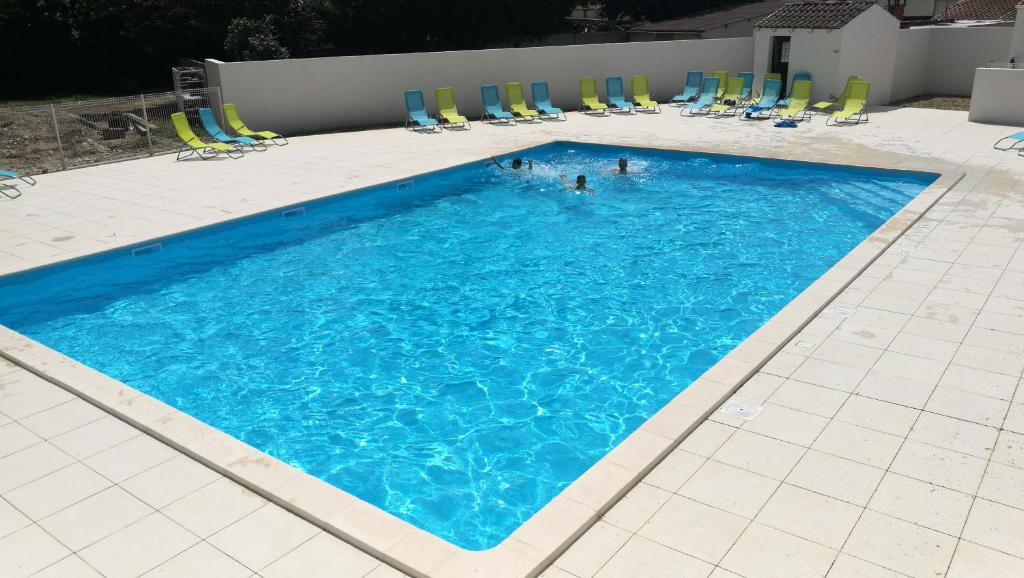 a large swimming pool with chairs and people in it at Camping Fleur d'Oleron in Saint-Pierre-dʼOléron