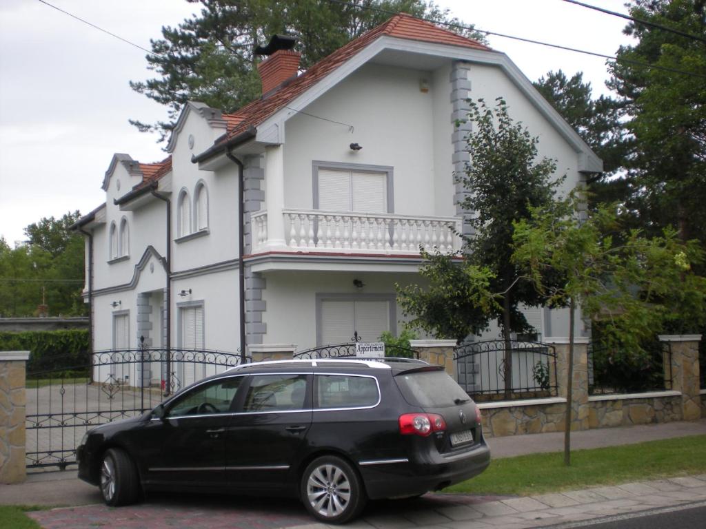 un coche negro estacionado frente a una casa blanca en Kentaur Apartmanház en Siófok