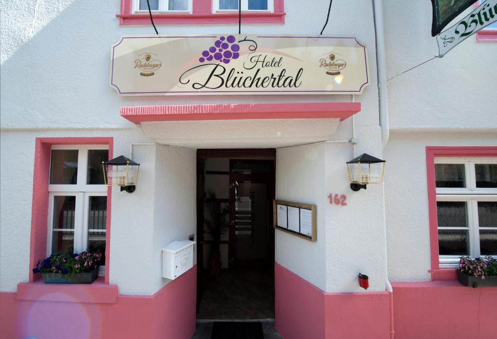 un bâtiment rose et blanc avec un panneau sur celui-ci dans l'établissement Hotel Blüchertal, à Bacharach