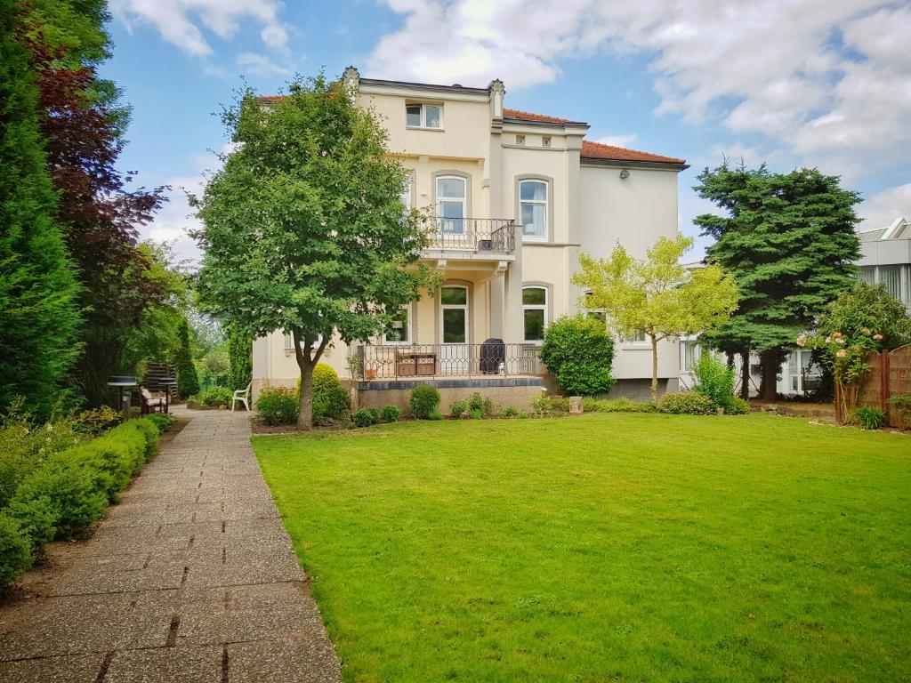 a large white house with a green yard at Einzigartige Jugendstil-Villa im Herzen von Kassel in Kassel