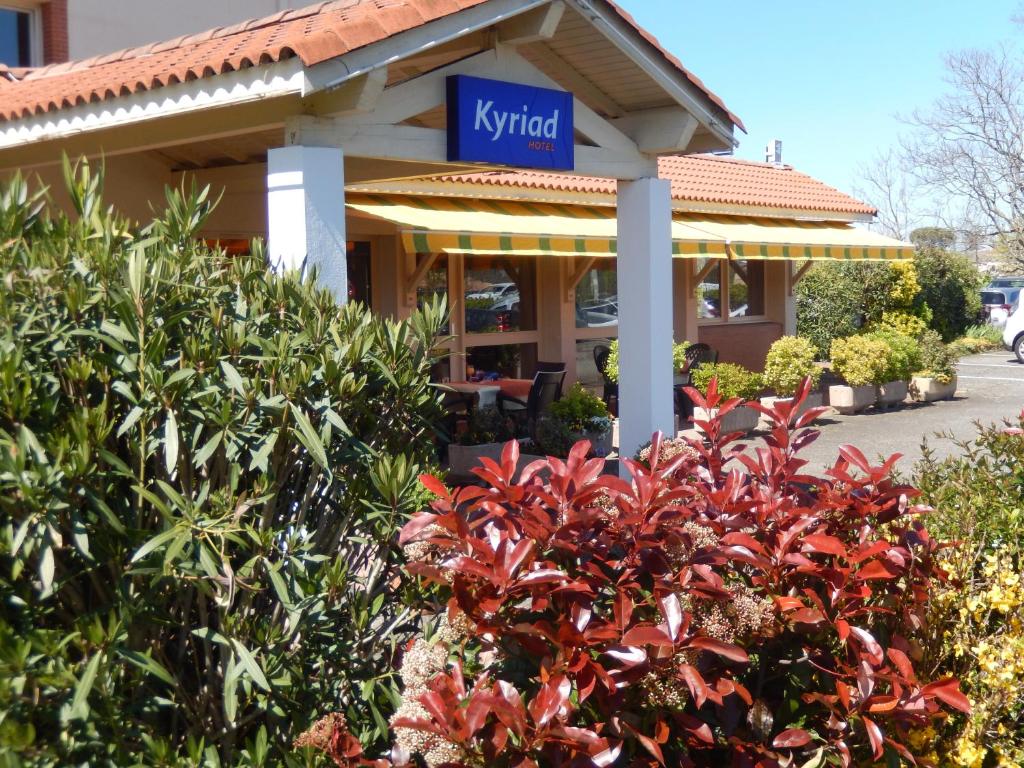 un restaurant avec un panneau sur un bâtiment dans l'établissement Kyriad Toulouse Blagnac Aéroport, à Blagnac