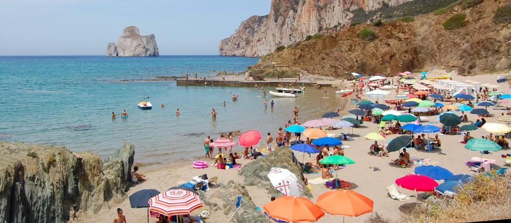 a crowd of people on a beach with umbrellas at La casetta di MrBee in Iglesias