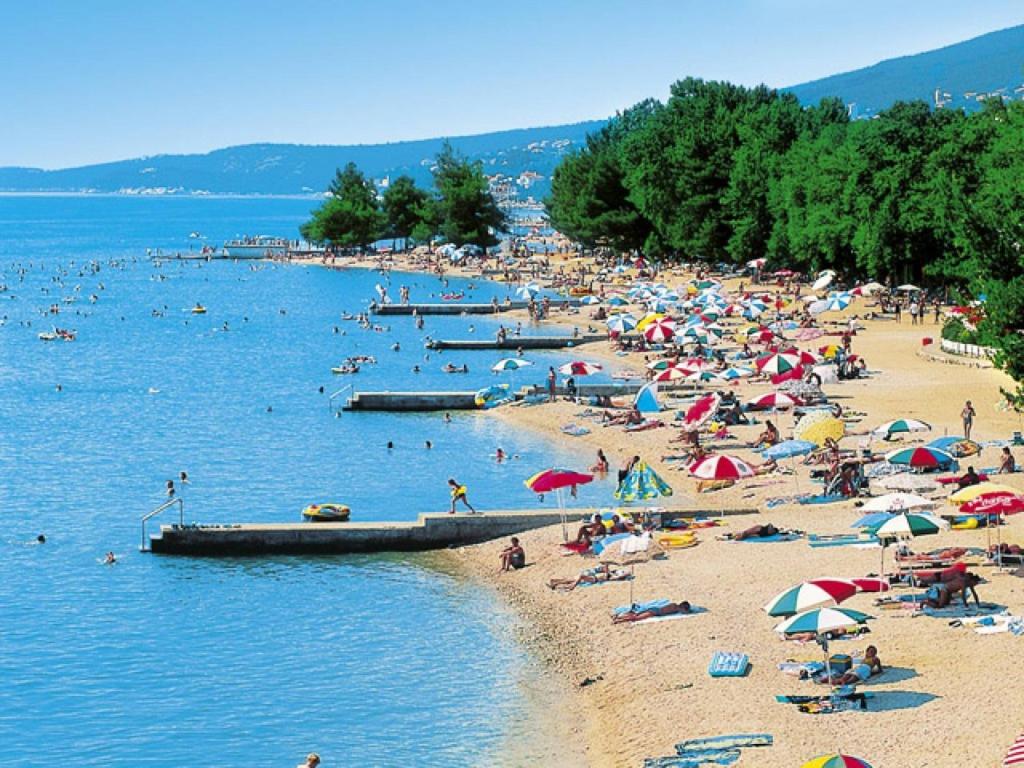 a beach with a bunch of people on the sand and water at Apartman Maria in Crikvenica