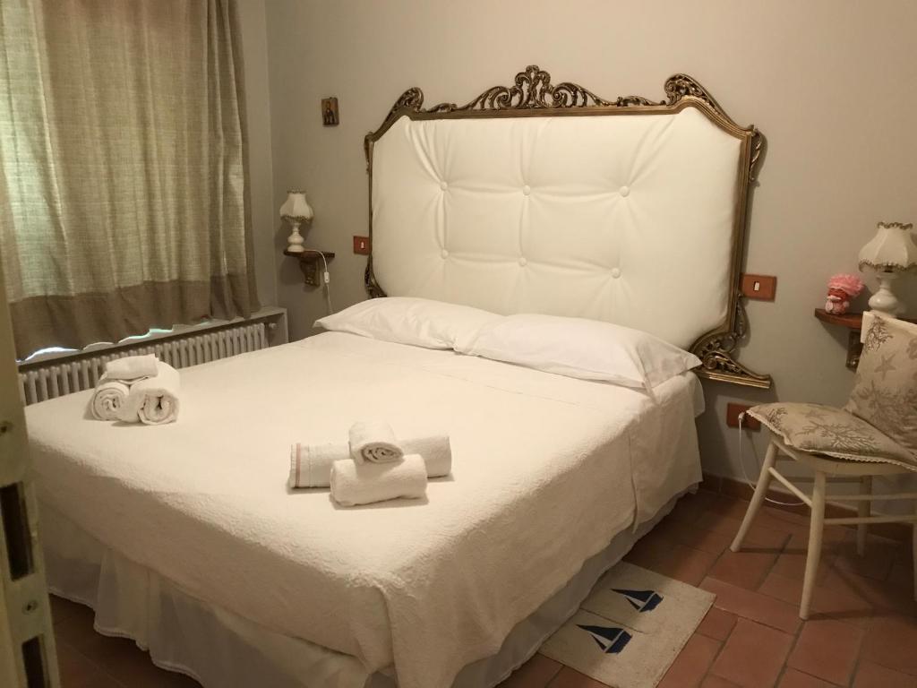 una camera da letto con un letto bianco e asciugamani di Ancora bilocale a Marina di Massa
