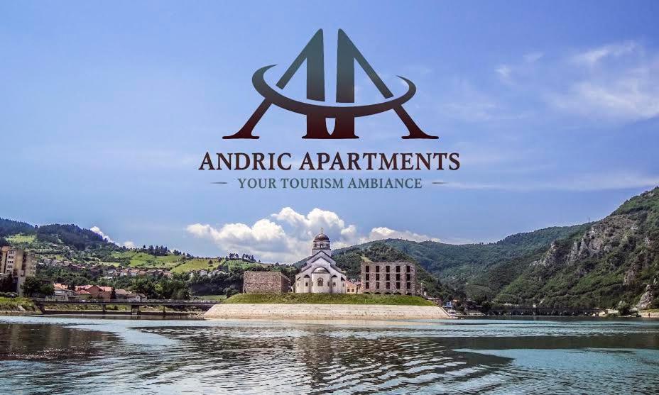 a sign for anantigrapher apartments with a building in the water at Apartman Andrić in Višegrad