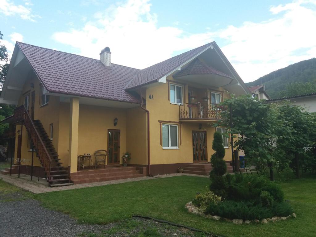 a yellow house with a porch and a balcony at U Lyudmily in Karpaty