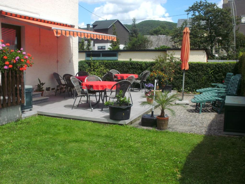 un patio con tavoli, sedie e ombrellone di Gästehaus Ruth Andrae a Bruttig-Fankel