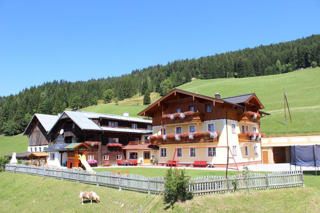 a large house in a field with a cow in front of it at Unterhagmooshof in Radstadt