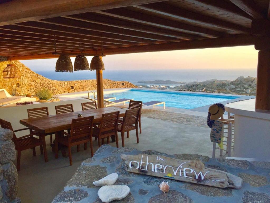 ein Esszimmer mit einem Tisch und Meerblick in der Unterkunft Otherview Villa in Super Paradise Beach