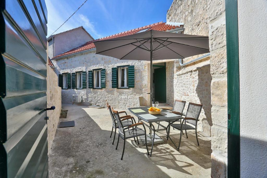 a table and chairs with an umbrella in front of a building at Vacation home Vibor in Dračevica