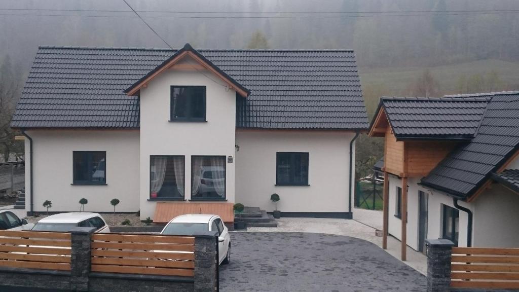 a white house with a black roof at Apartamenty Olimpijskie Szczyrk in Szczyrk