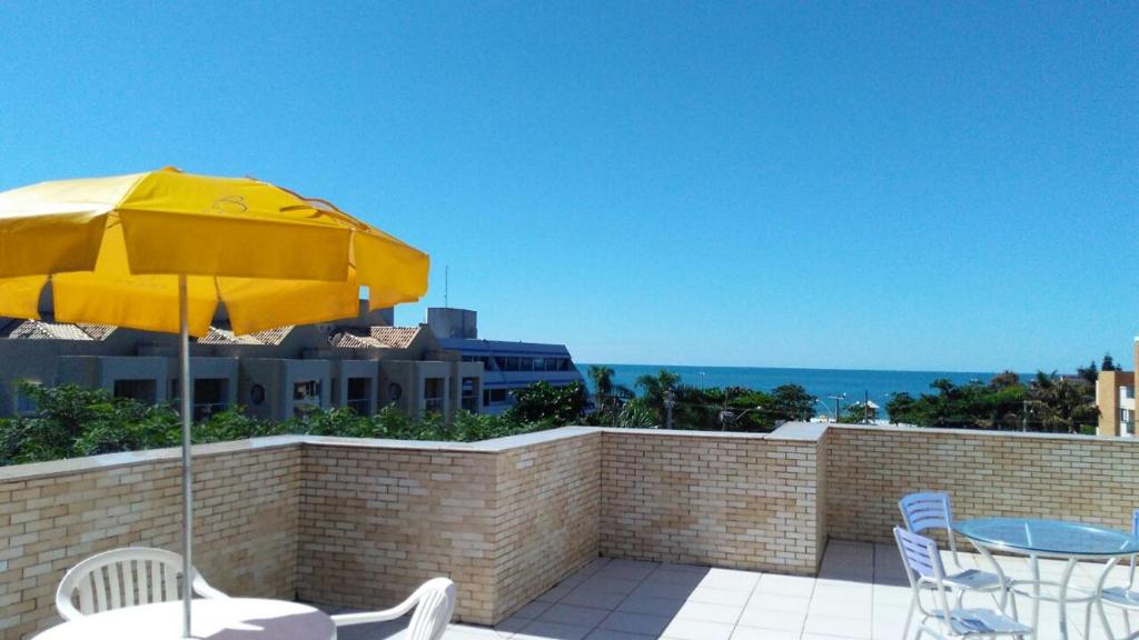 eine Terrasse mit einem gelben Regenschirm, einem Tisch und Stühlen in der Unterkunft Brava Apart Hotel in Florianópolis