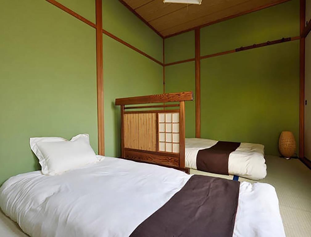 a bedroom with two beds and a green wall at CITY HOTEL Nishikujo Residence 1 in Osaka