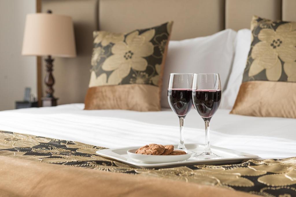 two glasses of wine and a plate of food on a bed at Golden Star Motel in Christchurch